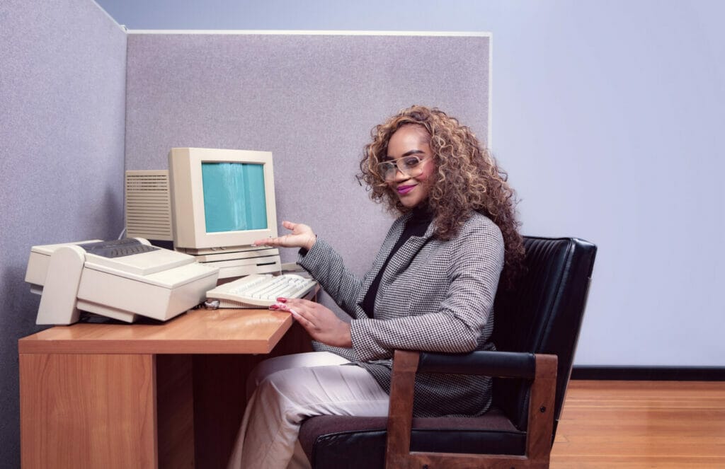 A woman in front of her vintage computer. 1980s office.